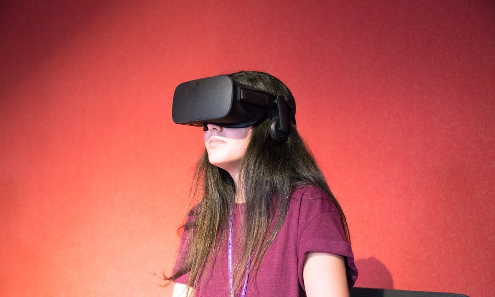 A visitor inside the Untitled Realities installation wearing an Oculus Rift, lit against a red wall